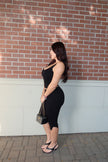 Side view of a model wearing a fitted black ribbed tank and capri set
