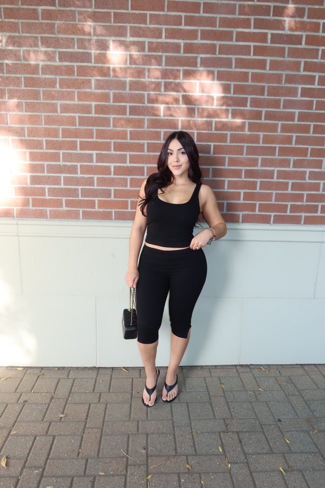 Front view of a model wearing a black ribbed tank and capri set