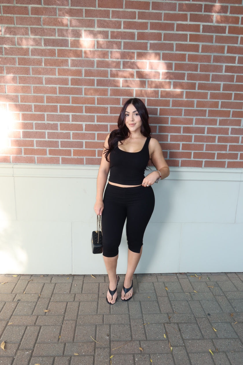 Front view of a model wearing a black ribbed tank and capri set