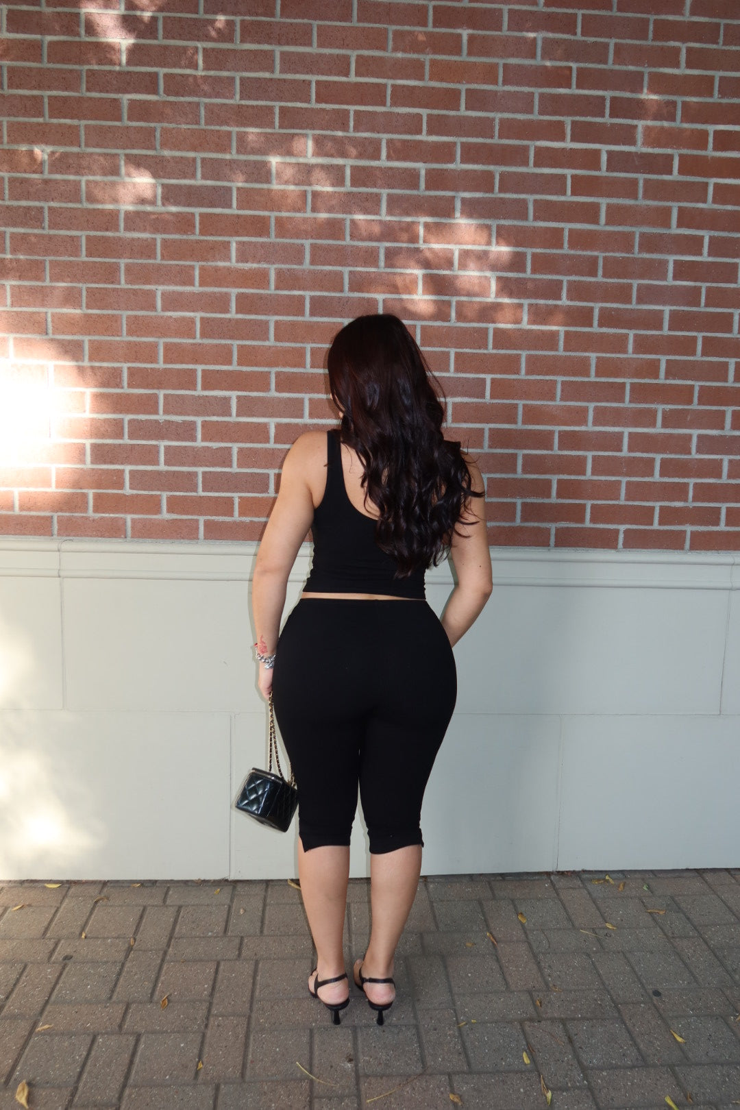 Back view of a model wearing a black ribbed tank and capri set