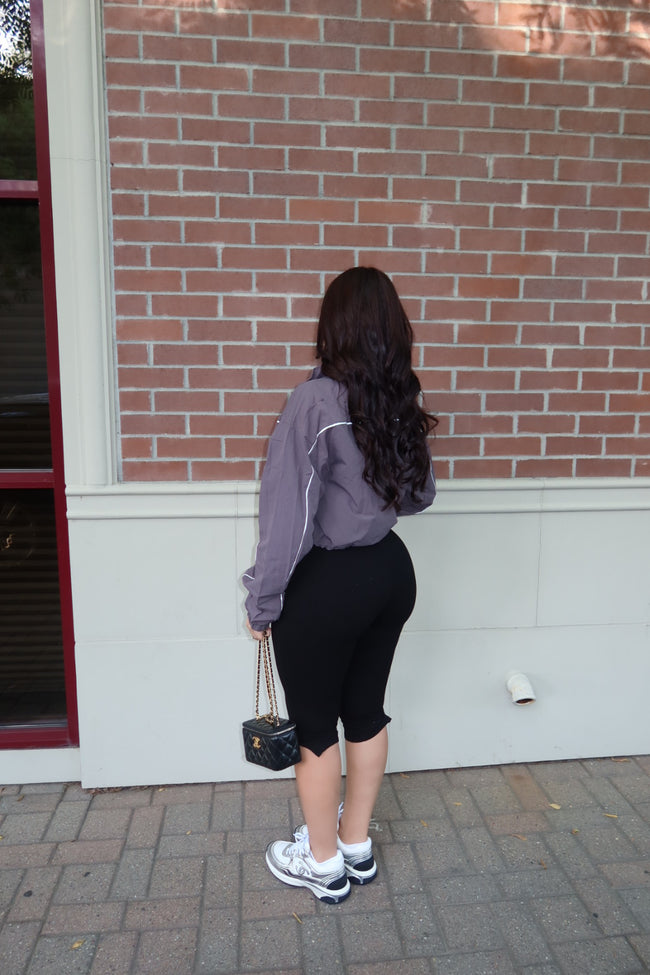Model wearing a cropped nylon windbreaker styled with casual bottoms